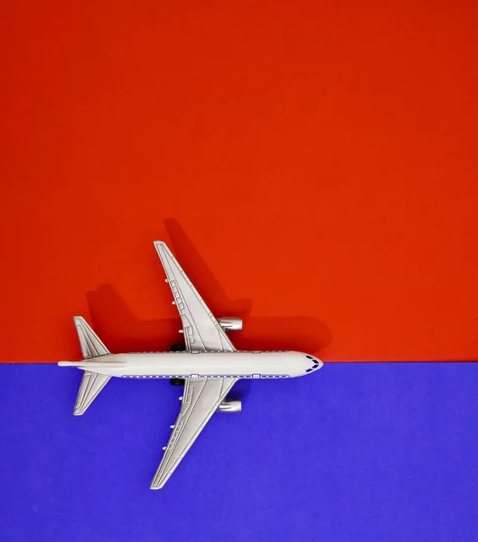 金属製のおもちゃ 赤と青の紙の背景に飛行機 旅行と交通のアイデア — ストック写真