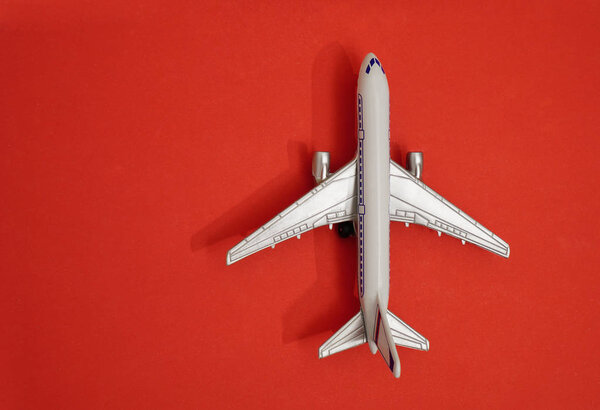 metal toy - airplane  on red  paper background. travel and transportation idea.