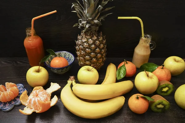 two Glass bottles of fruit juice on black wooden table