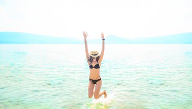 young one woman jumping in ocean at day light. 