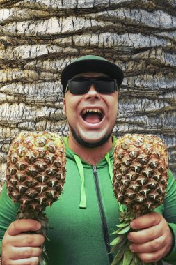 sakal yetişkin adam duvar arka plan karşı iki ananas ile dans. . 