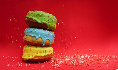 Üç renkli donut izole kırmızı zemin üzerine yan görünüm. Gıda zemin. boş kopya alanı yazıt için. 