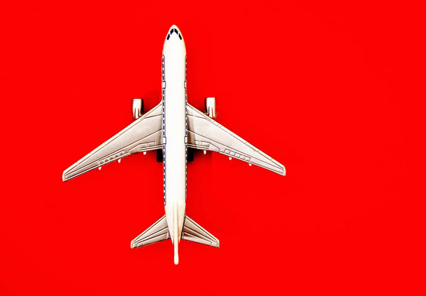 metal toy - airplane  on red  paper background. travel and transportation idea.