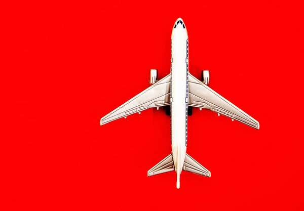 metal toy - airplane  on red  paper background. travel and transportation idea.