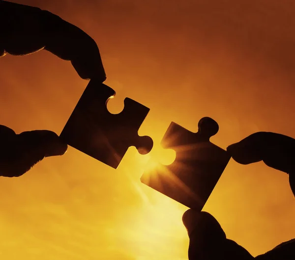 hands  with  puzzle pieces with sky background.