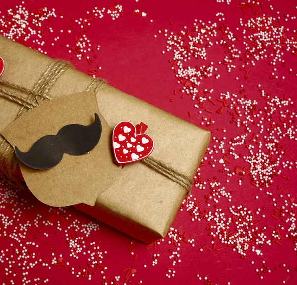 Father\'s Day. gift box  on red paper background. Happy fathers day concept. sticker in the form of black mustache.