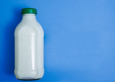 Kapalı cam şişe süt mavi Kağıt arka plan üzerinde. 