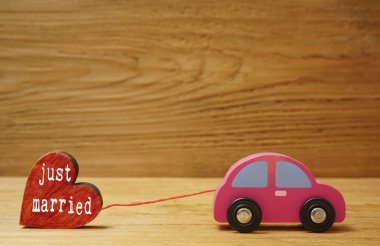 Ahşap tahta arka plan üzerinde izole küçük bir ahşap kırmızı kalp figürü ile ahşap araba.