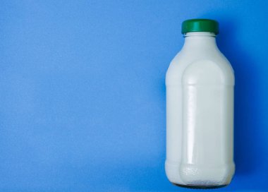 Kapalı cam şişe süt mavi Kağıt arka plan üzerinde. 