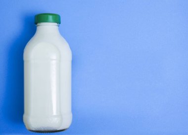 Kapalı cam şişe süt mavi Kağıt arka plan üzerinde. 