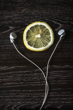 sarı limon ve mini beyaz kulaklık dilim. siyah ahşap masaya izole. 