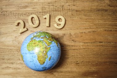 mutlu yeni yıl 2019 ahşap masa doku üzerinde yuvarlak dünya ile. Boş kopya alanı yazıt veya nesneler için