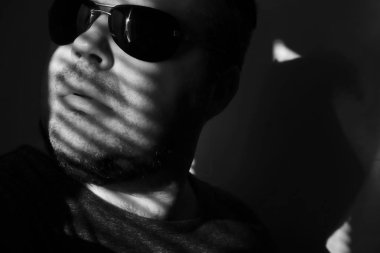 Vitrinlere bakıyor güneş gözlüklü adam; Şerit Gölgelerin içinden güneşlikler