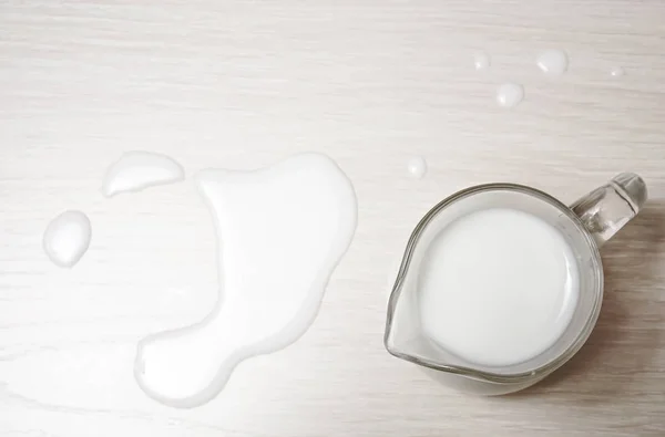glass jug of milk on a wooden background. top view. spilled milk.