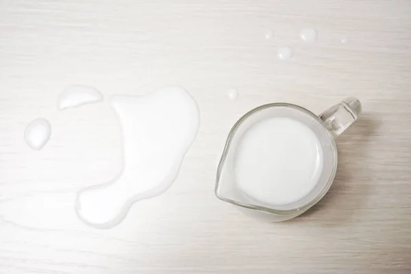 glass jug of milk on a wooden background. top view. spilled milk.