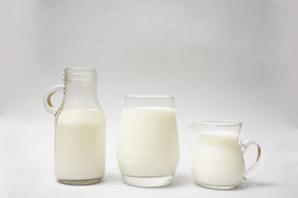 Milk bottle, jug and glass of milk isolated on  paper background