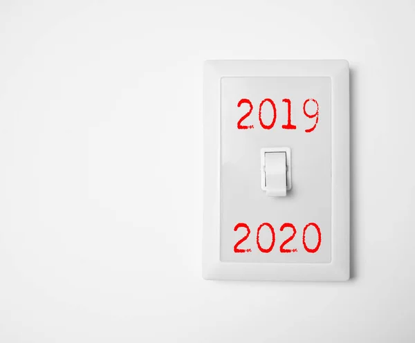 Classic white light switch hanging on the wall. switching between 2019 and 2020