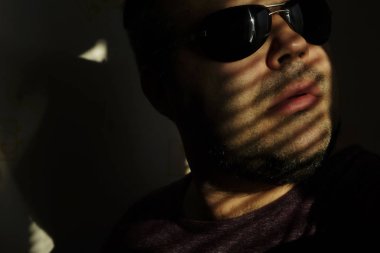 Vitrinlere bakıyor güneş gözlüklü adam; Şerit Gölgelerin içinden güneşlikler