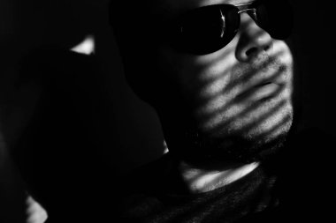 Vitrinlere bakıyor güneş gözlüklü adam; Şerit Gölgelerin içinden güneşlikler