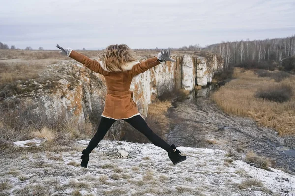 woman tourist in winter clothes jumping  against the background of snow-covered field.