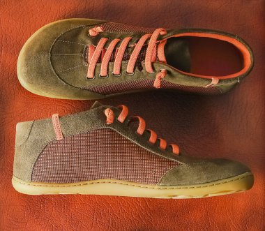 Flat lay of brown orange and green textile shoes,  on brown leather background