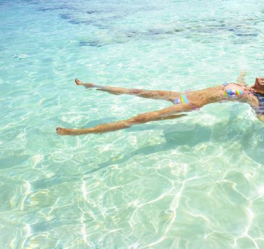 Renkli bikini su tropikal plajda yatan kadın.
