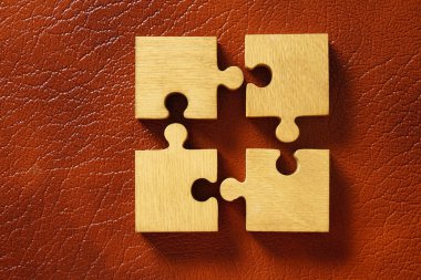 Deri arka plan üzerinde dört ahşap puzzle parçaları. bağlantı insanlar kavramı