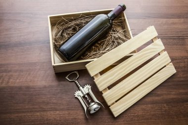 bir kırmızı şarap şişesi ahşap masa arka planda saman veya saman ve korkvida ile tahta kasa veya kutu yalan