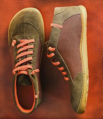 Flat lay of brown orange and green textile shoes,  on brown leather background