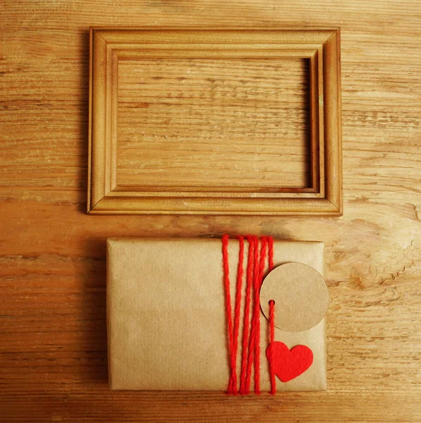 空白相框与老式礼品盒包裹在工艺纸在旧的木制桌子背景 顶视图 — 图库照片