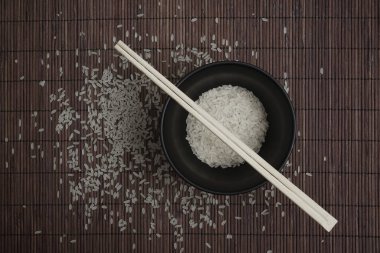 kahverengi bambu arka planda pirinç. kase üzerinde ahşap Chopsticks