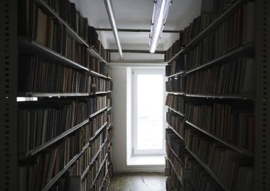 Pencerenin yanındaki beyaz kütüphane raflarında kitaplar. perspektifte eski kütüphane arka planı.
