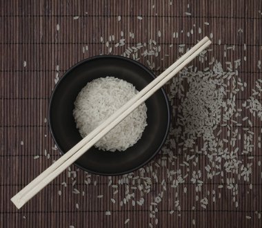 kahverengi bambu arka planda pirinç. kase üzerinde ahşap Chopsticks