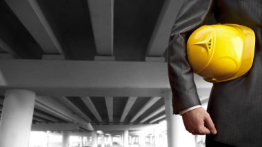 çalışan işçi güvenliği için sarı kask boş yeni modern bina arka plan üzerinde tutan.