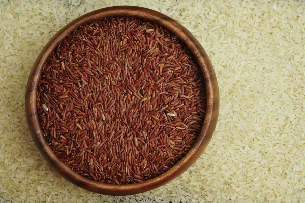 Brown and white wild rice in a wooden plate on a wooden background. space for text
