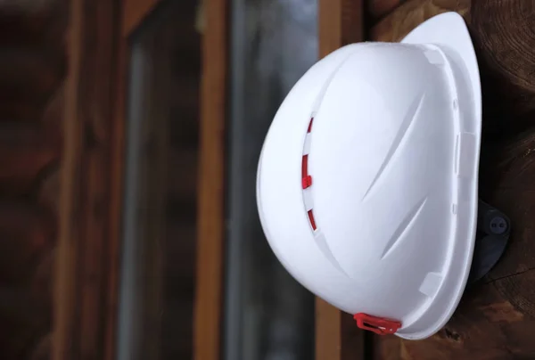 Construction hard hat hanging  on wooden house background