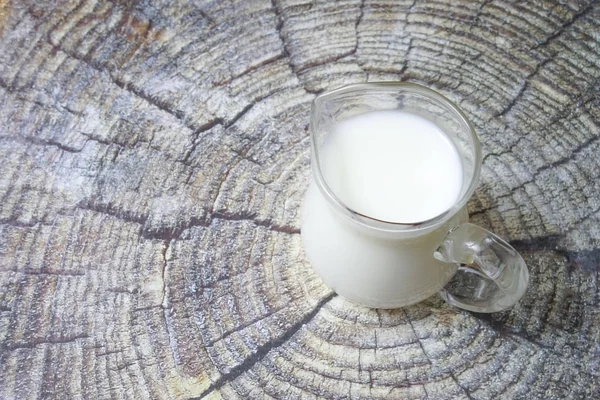 Krug Milch auf einem Baumstumpf Hintergrund — Stockfoto