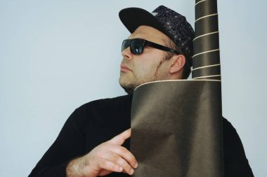 Beyaz duvar arka plan üzerinde siyah duvar kağıdı bir rulo ile kendine güvenen erkek iç mekan tasarımcısı. 