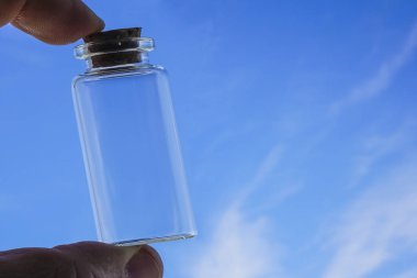 Erkek el Mavi gökyüzüne karşı şeffaf boş cam tutun. korked olabilir