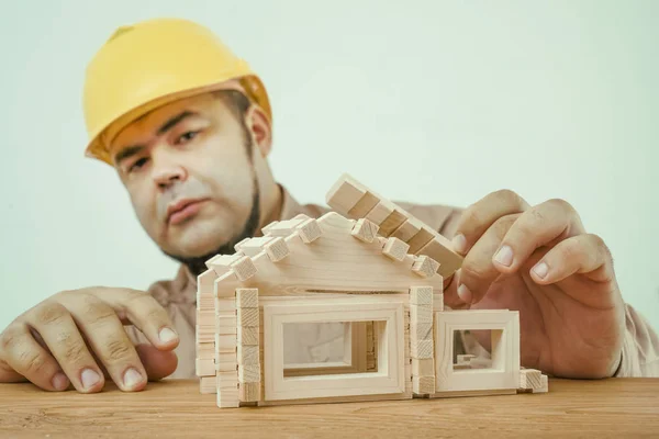 承包商和木制玩具的小屋或房子 在房子模型附近黄色头盔的建设者 — 图库照片
