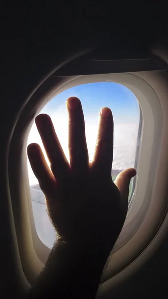 man\'s hand silhouette  on plane window. hello travel