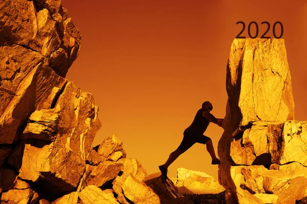 silhouette of business man reaching  2020 on the mountain. Free climbing on the mountain