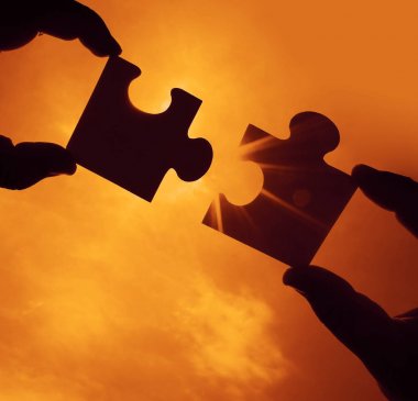 turuncu gökyüzü arka plan ile bulmaca parçaları ile eller. 