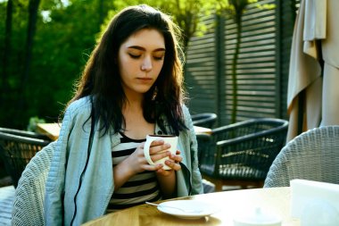 Kahve zamanı. Kaldırım kafede otururken kahve içen çekici genç kadın 