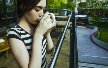 Sakin sabah genç kız lüks otel balkonunda içecek manzarası zevk kahvaltı kahve içme rahatlatıcı, yaz seyahat tatil.