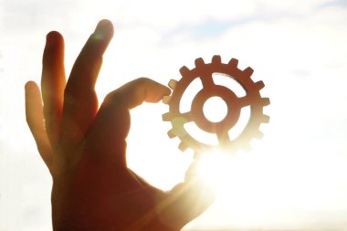 Beyaz arka plan üzerinde izole bir ahşap dişli tekerlek tutan erkek el. 