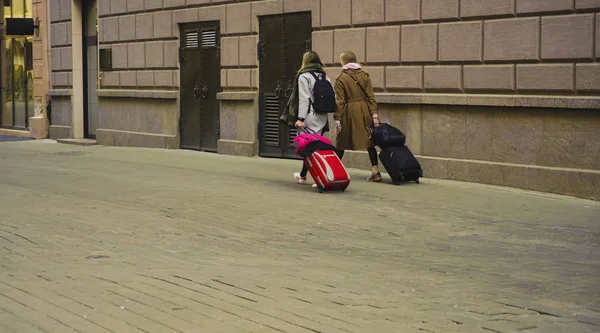 两个女孩拿着手提箱在人行道上走 — 图库照片