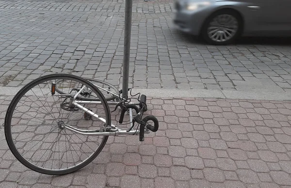 fallen parked  bicycle lie on cobbled stone.