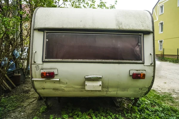 old rusty travel trailer (camper trailer, camper van, caravan). Caravan Trailer Near house. Summer Holidays Road Trip Travel Concept.
