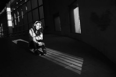 Neşeyle dinleniyor. Güzel genç kadın müzik dinliyor ve otoparkta yerde oturuyor. güneşli ışık ve yüzünde gölgeler